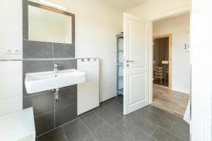 a white bathroom with a sink and a mirror at Ferienhaus-Belvedere-2-c in Blekendorf +29 photos