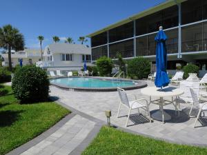 a pool with chairs and a table and a blue umbrella at Sunset Beach 101 Beach Front Unit in Holmes Beach