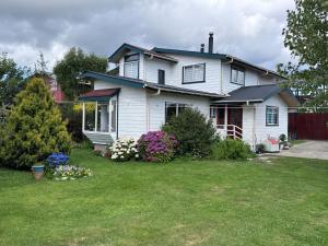 a white house with flowers in the yard at Hospedaje Brisas de Frutillar in Frutillar