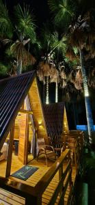 a wooden deck with chairs and palm trees at night at Chalé dos Buritis 02 in Chapada dos Guimarães +9 photos