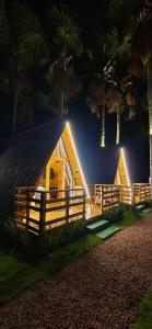 a cabin with a fence and palm trees at night at Chalé dos Buritis 02 in Chapada dos Guimarães