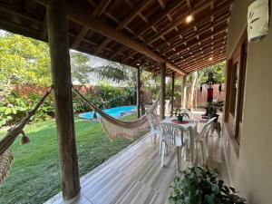 a porch with a hammock and a swimming pool at Casa das Alpinias - Trancoso in Trancoso