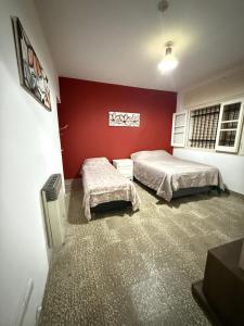 a bedroom with two beds and a red wall at HOSTEL del MUNDO in Villa María +8 photos