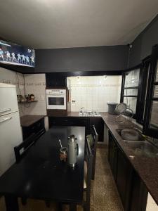 a kitchen with a black table and a white refrigerator at HOSTEL del MUNDO in Villa María