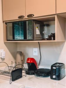 a kitchen counter with a red toaster and a microwave at Chale Container no Centro de Petrópolis in Petrópolis