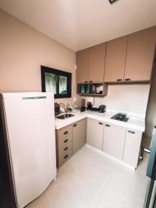 a kitchen with white cabinets and a white refrigerator at Chale Container no Centro de Petrópolis in Petrópolis
