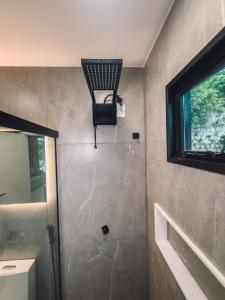 a bathroom with a shower with a light on the wall at Chale Container no Centro de Petrópolis in Petrópolis +21 photos
