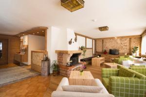 a living room with green couches and a fireplace at B&B Residence Adria in Corvara in Badia