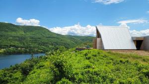 a house on a hill next to a river at Cedar Peak - Design-Forward Barrier-Free Chalet in Grand-Etang