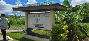a man walks past a sign at a forest hotel at Yatu Lau Transit Hotel in Nadi