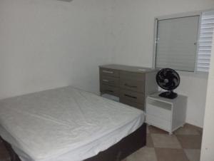 a bedroom with a bed and a dresser and a window at Hostel da Duda II in Itanhaém +3 photos