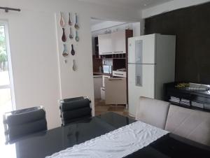 a kitchen with a glass table and a white refrigerator at Hostel da Duda II in Itanhaém