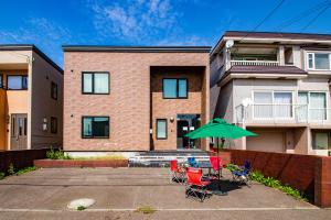 a patio with chairs and an umbrella in front of a house at THE WORLDWIDE HOUSE in Sapporo