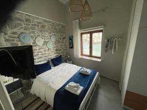 a bedroom with a bed with blue sheets and a tv at Carnagio All Season in Kavála