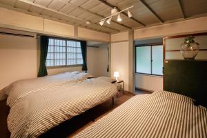 a bedroom with two beds and two windows at Hinosawa Riverside Lodge 水遊び宿日野沢 in Minano