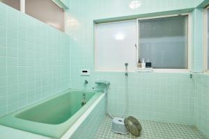 a bathroom with a tub and a toilet in it at Hinosawa Riverside Lodge 水遊び宿日野沢 in Minano