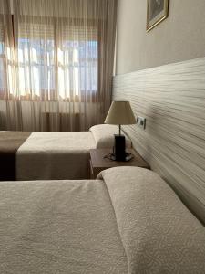 ein Hotelzimmer mit zwei Betten und einer Lampe auf einem Tisch in der Unterkunft Hotel Can-Vic in Guadalajara
