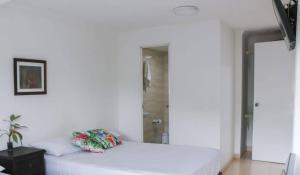 a white bed with two pillows on it in a room at Hospedaje s o s in Cali
