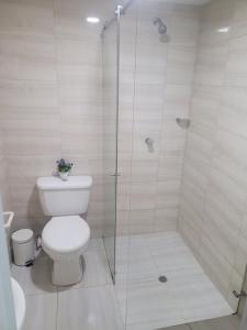 a bathroom with a toilet and a glass shower at Hospedaje s o s in Cali