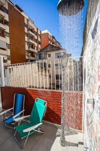 two chairs and a water fountain on a rooftop at Espaço Sideral - Quartos com ar-condicionado, 5min Estádio Maracanã, 8min UERJ, shopping, 12min metrô, wi-fi 300mbp, ampla área comum com cozinha - prático e confortável in Rio de Janeiro