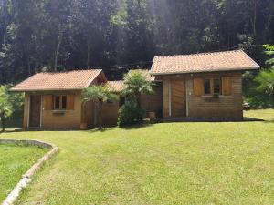 a small house with a grass yard next to a house at Chalés Beira Rio in Santo Antônio do Pinhal