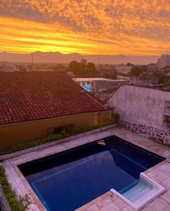 a swimming pool on top of a house with a sunset at Hostel Casarão SV in São Vicente +34 photos