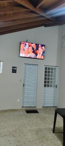 two garage doors in a white room with a television on the wall at Edícula Caramano in Jaú