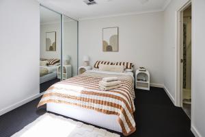 a white bedroom with a bed and a mirror at Water's Edge 4x4 Townhouse in Falcon