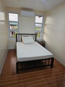 ein Bett in einem Zimmer mit zwei Fenstern in der Unterkunft Kuyang's Place in Bulala