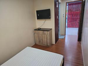 ein Zimmer mit einem Bett und einem Flachbildfernseher in der Unterkunft Kuyang's Place in Bulala