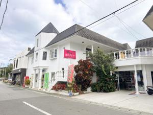 a white building with a sign on it on a street at ゲストハウスまるとく in Yoron