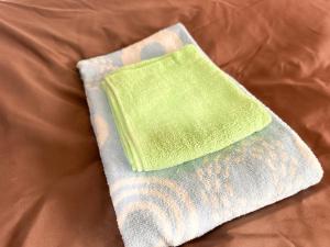 a green and white sock sitting on top of a bed at ゲストハウスまるとく in Yoron