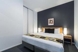 a bedroom with a large bed and a black wall at Mantra 100 Exhibition in Melbourne