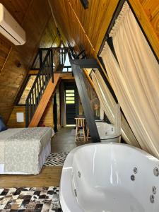 a bathroom with a bath tub and a bed in a room at Pousada Flor do Campestre in Urubici