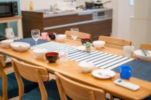 a wooden table with wine glasses and plates on it at 家族の笑顔 希望ヶ丘ビーチまで徒歩5分でのんびり家族ステイ Coral Onnason in Onna