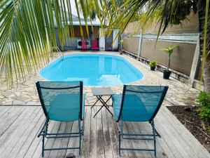two chairs sitting in front of a swimming pool at Sermie T4 à kourou avec piscine in Kourou