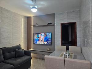 a living room with a couch and a tv on a wall at Brisa Do Mar in Saquarema