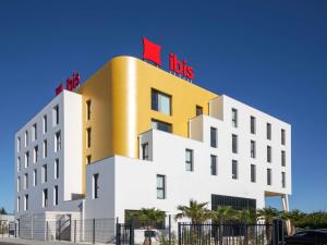 a hotel with a red sign on top of it at Ibis Marseille Marignane Technopole in Marignane