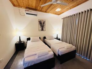 two beds in a room with two lamps and curtains at Lone Star Residence in Jaffna