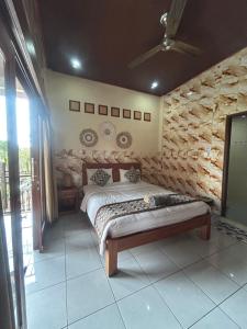 a bedroom with a bed and a stone wall at Nami House in Ubud