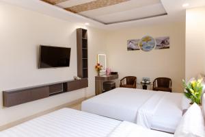 a hotel room with two beds and a flat screen tv at Boss Palace Hotel in Ho Chi Minh City