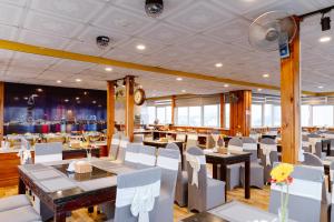 a restaurant with white chairs and tables and a clock at Boss Palace Hotel in Ho Chi Minh City