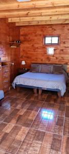 a bedroom with a bed in a wooden cabin at Alojamiento Pamela in Coñaripe