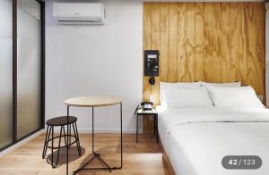 a bedroom with a bed and a stool next to a table at Just Sleep Hotel Jihaeng Station in Tongduch'ŏn