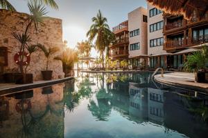a hotel swimming pool with palm trees and buildings at Esplendor by Wyndham Isla Mujeres Boutique All Inclusive in Isla Mujeres