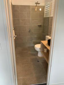 a bathroom with a toilet and a glass shower at Batemans Bay Lodge in Batemans Bay