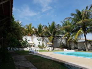 a swimming pool with chairs and umbrellas next to a house at Hotel blue Ocean 3 in Parnamirim