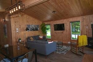 a living room with a couch and a tv at Refuge du Kodiak BORD DE L EAU in Sainte-Germaine-du-Lac-Etchemin
