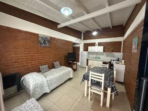 a room with a bed and a table and a kitchen at M&M Cipolletti in Cipolletti