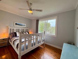 a bedroom with a white crib and a window at Watts @ Callala Beach-Pet Friendly in Callala Beach
